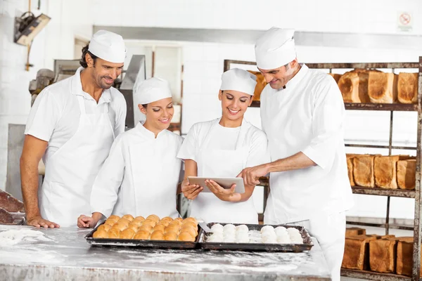 Panettieri maschili e femminili che utilizzano la tavoletta digitale nel forno — Foto Stock