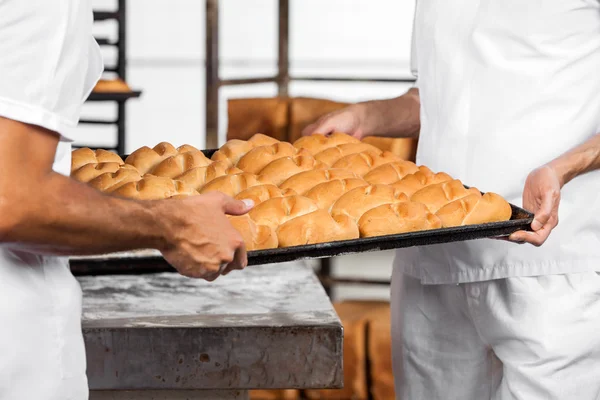 Sección media de panaderos llevando panes en bandeja — Foto de Stock