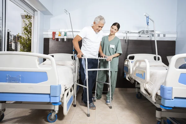 Sjuksköterska medhjälpande Senior patienten i att använda Walker på Rehab Center — Stockfoto