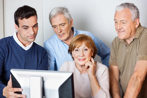 Tutor Assisting Senior People In Using Computer At Class Stock Picture