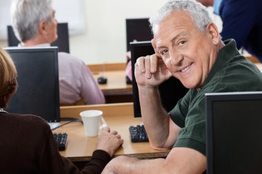 Bilgisayar sınıfı içinde oturan mutlu üst düzey adam portresi