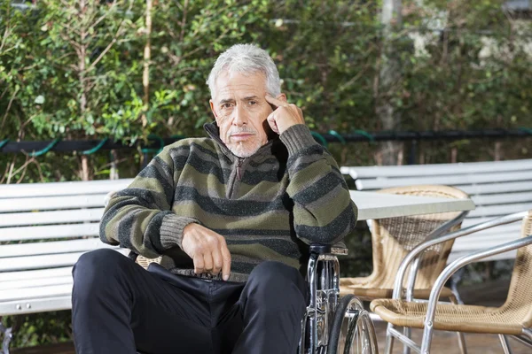 Fundersam Senior manliga patienten sitter i rullstol på gräsmattan — Stockfoto