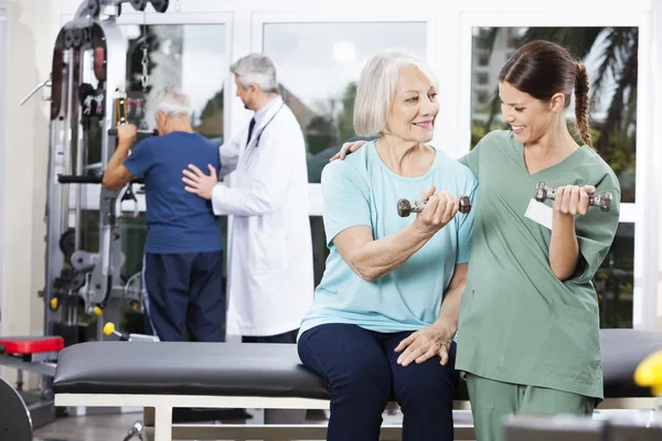Krankenschwester führt Seniorin beim Gymnastik mit Hantel — Stockfoto
