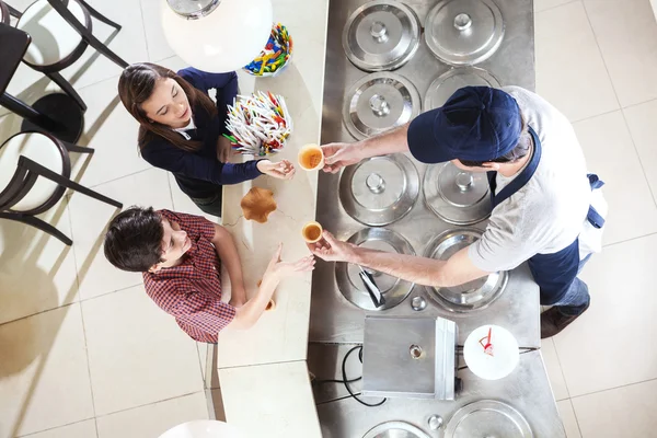 Garçom dando copos para os clientes no salão de sorvete — Fotografia de Stock