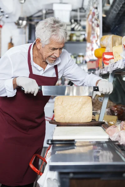 Vendedor de rebanadas de queso con cuchillo en la tienda —  Fotos de Stock