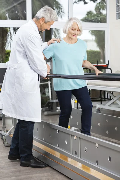 Médico Assistindo Paciente Sênior Para Caminhar Entre Bares — Fotografia de Stock