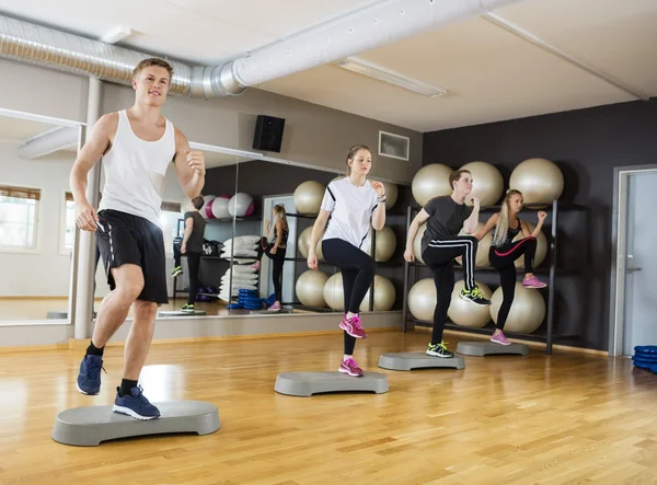 Hommes et femmes effectuant l'exercice d'étape dans le gymnase — Photo