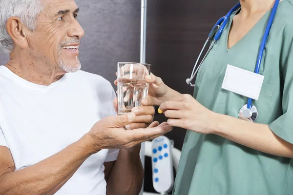 Sezione centrale dell'infermiera che dà la medicina e l'acqua al paziente anziano — Foto Stock