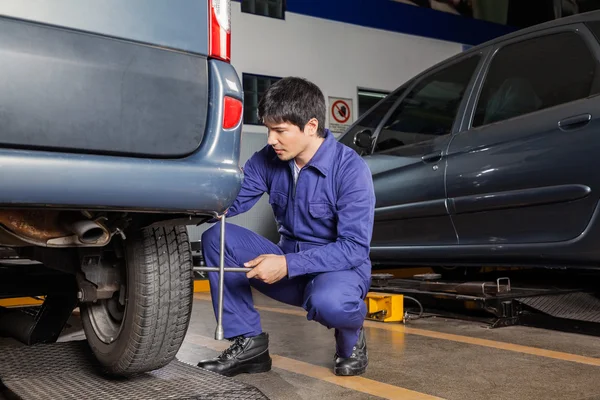 Technicien utilisant la clé de jante pour réparer le pneu de voiture — Photo