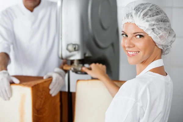 Selbstbewusste Bäckerin setzt Schneidemaschine in Bäckerei ein — Stockfoto