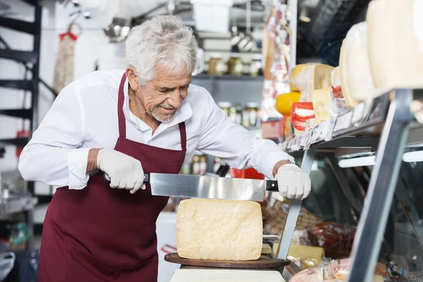 Salesman Slicing Cheese With Double Handled Knife In Shop — Stock Photo, Image