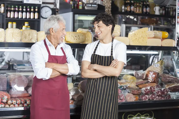 Skrattande försäljare med armar korsade i ost butik — Stockfoto
