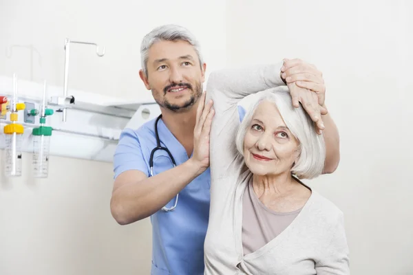 Fisioterapeuta ayudando al paciente mayor con ejercicio de mano — Foto de Stock