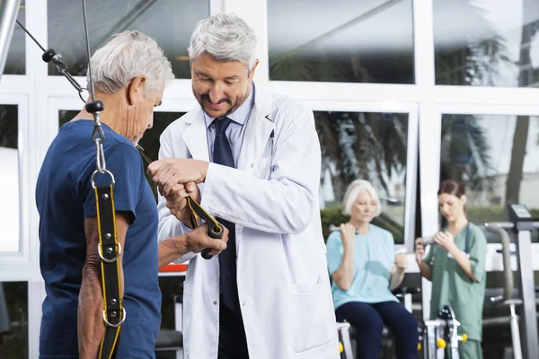 Medico Assistere l'uomo anziano con banda di resistenza — Foto Stock