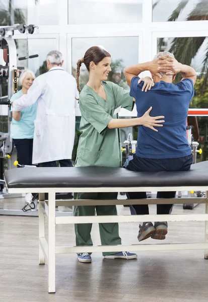 Smiling Female Physiotherapist Assisting Senior Man In Exercisin — Stock Photo, Image