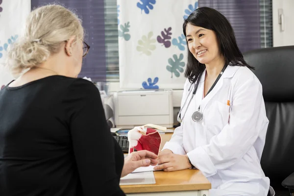 Médico ortopédico mirando al paciente femenino en el escritorio — Foto de Stock