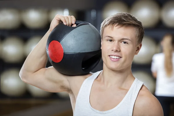 Hombre manteniendo la bola de la medicina en el hombro en el gimnasio — Foto de Stock