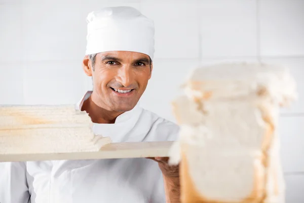 Volwassen mannelijke Baker met sneetjes brood — Stockfoto