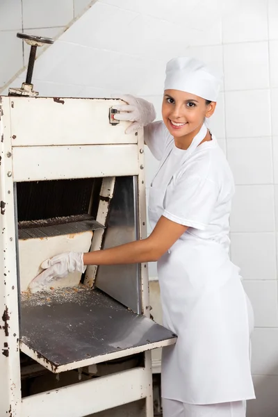 Kvinnliga bagare med brödet Slicer på bageriet — Stockfoto