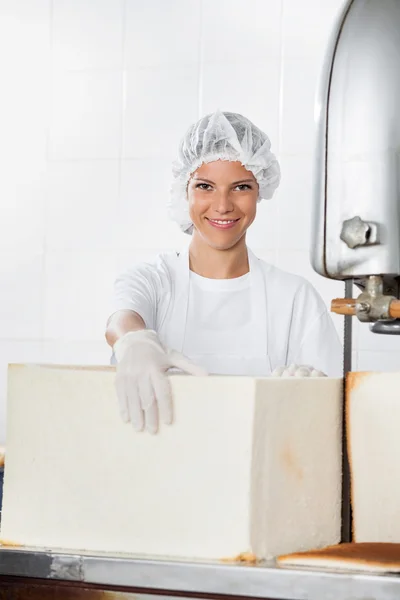 女面包师面包面包站在切割机 — 图库照片