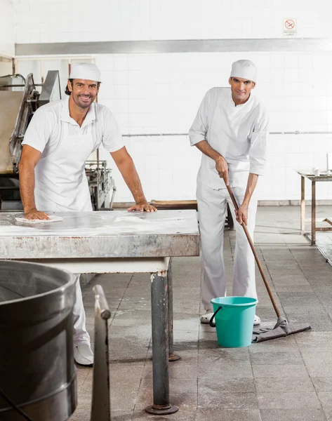 Vertrouwen mannelijke bakkers In Uniform schoonmaken bakkerij — Stockfoto