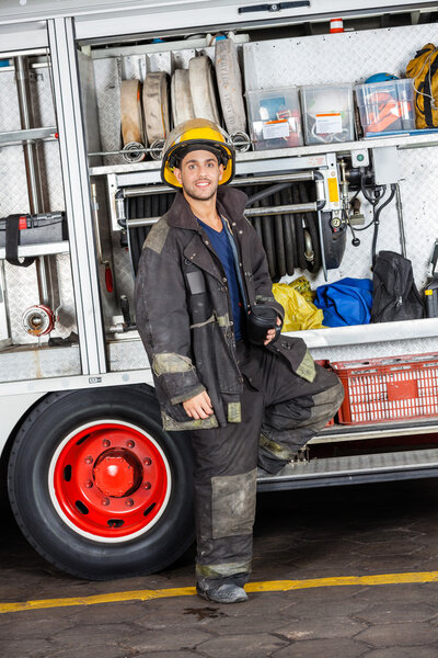 Confident Fireman Standing By Truck At Station