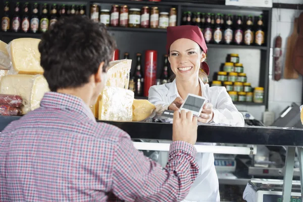 Продавец принимает платежи от клиента в сырном магазине — стоковое фото