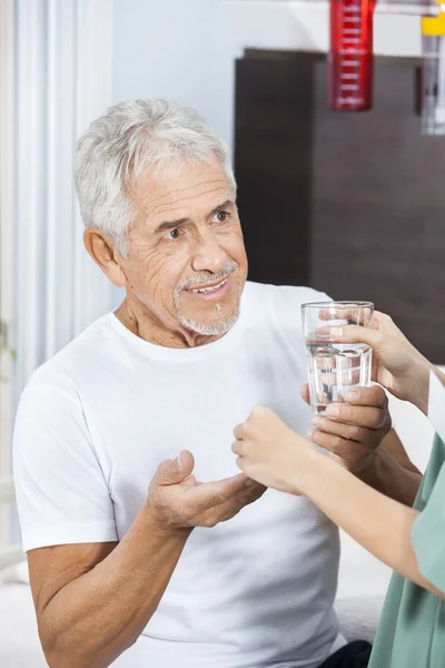 Krankenschwester gibt Patientin Medikamente und Wasserglas — Stockfoto