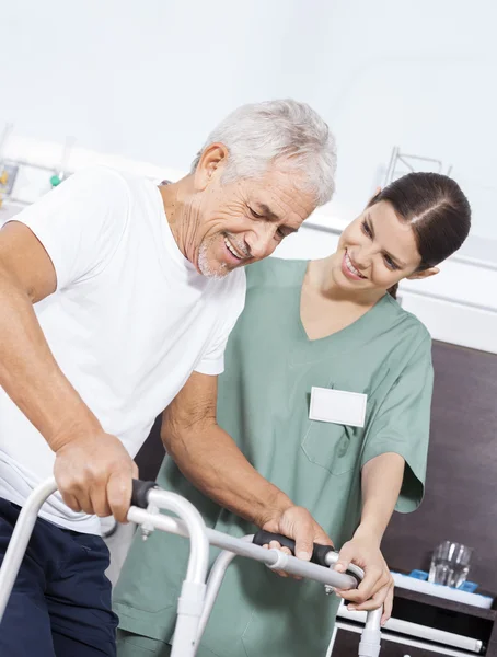 Verpleegkundige kijken naar Senior patiënt met behulp van Walker In Rehab Center — Stockfoto