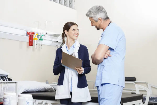 Fysiotherapeut Klembord te houden terwijl het kijken naar mannelijke Colleagu — Stockfoto