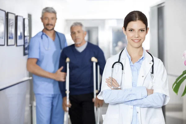 Femme médecin debout avec collègue et patient âgé dans le dos — Photo