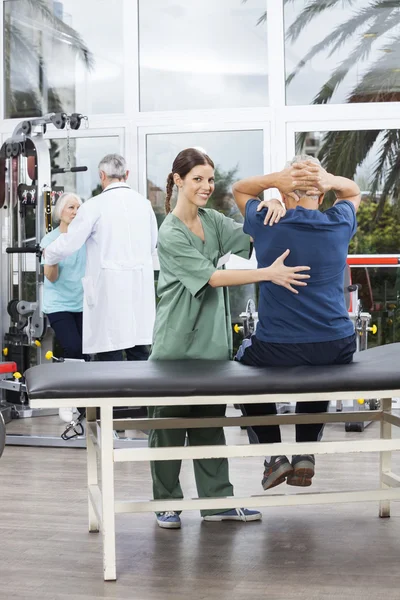 Fisioterapeuta Feminina Assistindo Homem Sênior no Exercício — Fotografia de Stock