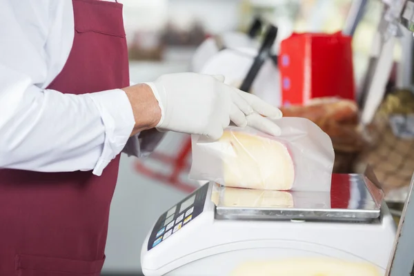 Försäljaren inslagning ost på vikt skala — Stockfoto