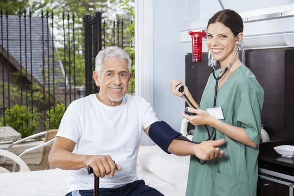 シニア マン血圧チェックで女性看護師 — ストック写真