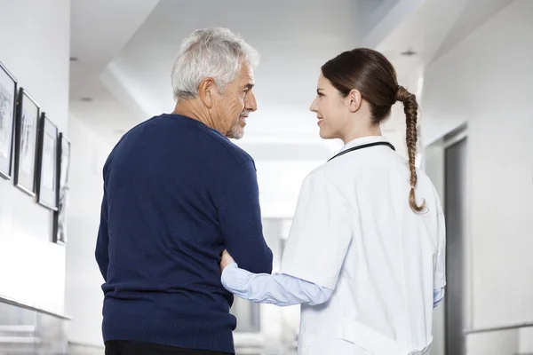 Médico femenino sosteniendo brazo de hombre mayor en centro de rehabilitación —  Fotos de Stock