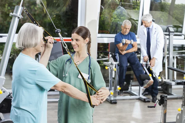 Verpleegkundige meewerkende Senior vrouw met weerstand Band oefening — Stockfoto