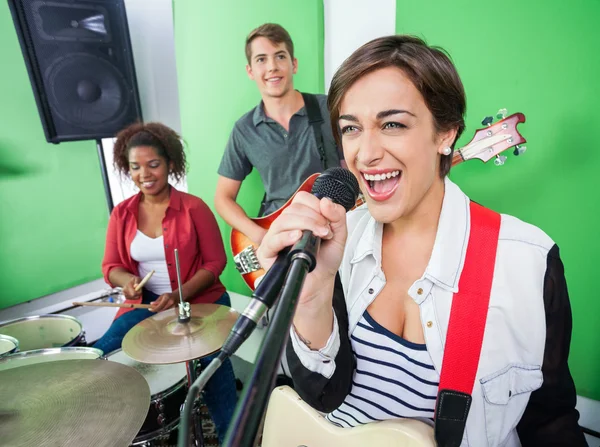 Vzrušená žena zpívá když kapela hrající hudební nástroj — Stock fotografie