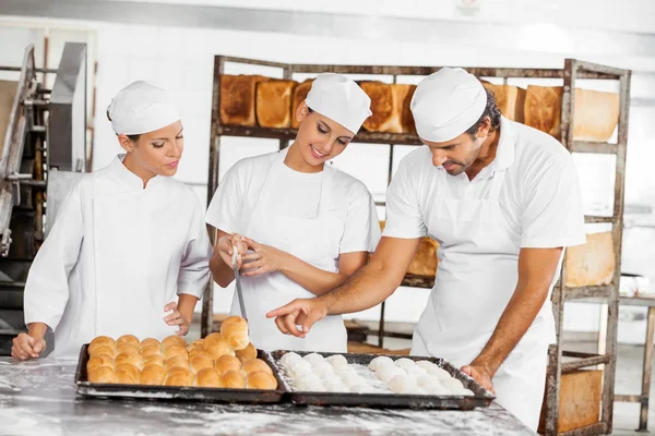 Panaderos analizando panes en la mesa en panadería —  Fotos de Stock