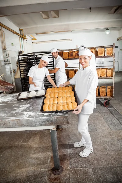 Feliz Baker mostrando panes horneados en panadería — Foto de Stock
