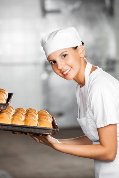 Happy Female Baker con panes frescos en bandeja para hornear — Foto de Stock