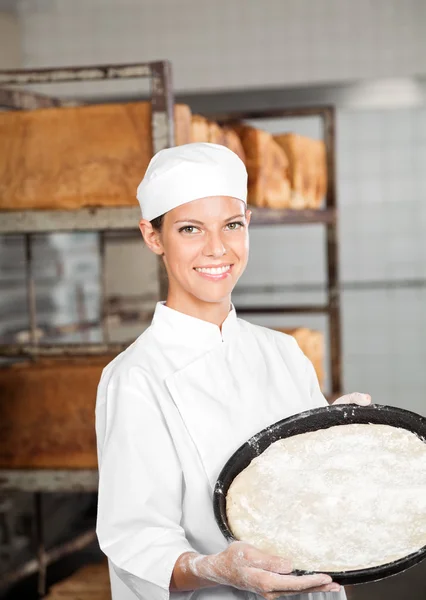 Selbstbewusste Bäckerin hält Teigblech beim Bäcker — Stockfoto