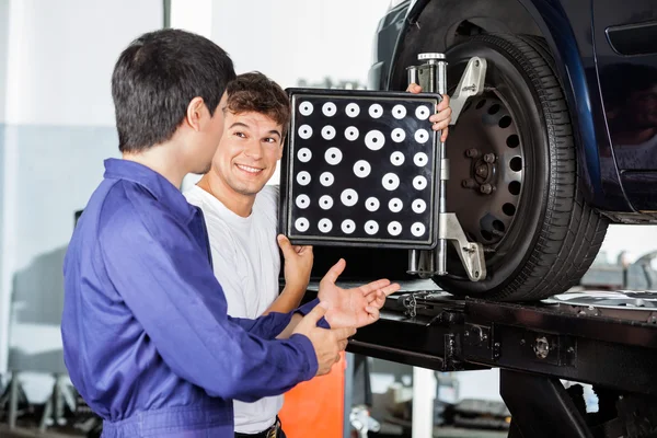 Mecánico con su colega mientras usa el alineador de ruedas —  Fotos de Stock