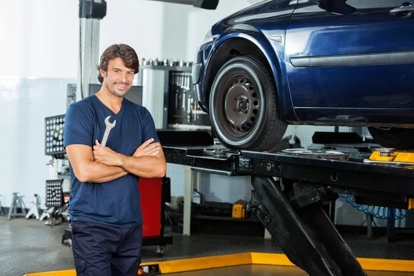 Selbstbewusster Mechaniker steht mit verschränkten Armen in der Garage — Stockfoto