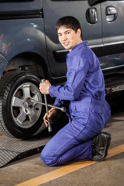 Confident Mechanic Fixing Car Tire at Garage — стоковое фото