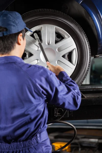 Técnico de llenado de aire en el neumático del coche en el garaje — Foto de Stock