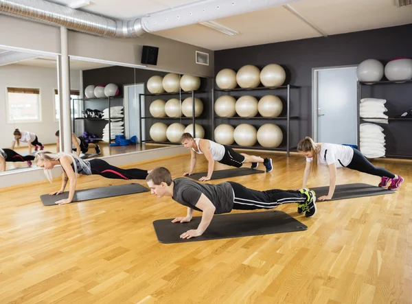 Amis effectuant l'exercice de planche dans le gymnase — Photo