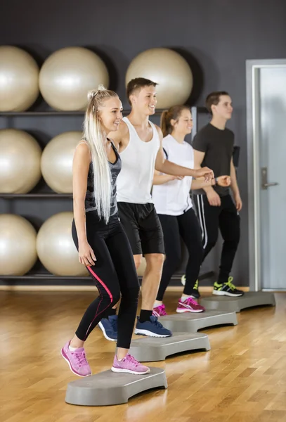 Amigos realizando ejercicio aeróbico paso en el gimnasio —  Fotos de Stock