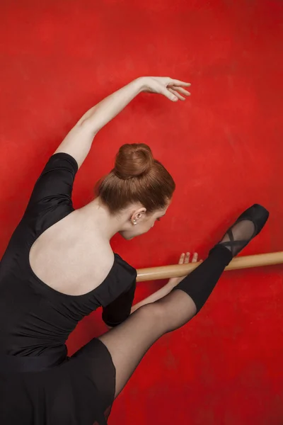 Baletka, táhnoucí se na Barre červené zdi — Stock fotografie