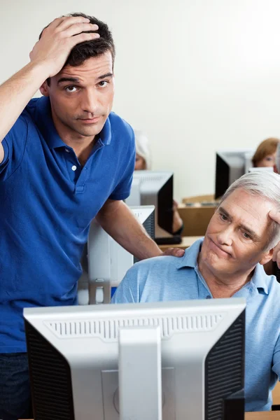 Insegnante irritato con l'uomo anziano che utilizza il computer in classe — Foto Stock