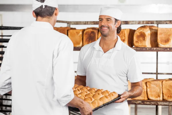 Piekarz z kolega przewożących bochenków chleba w zasobniku — Zdjęcie stockowe